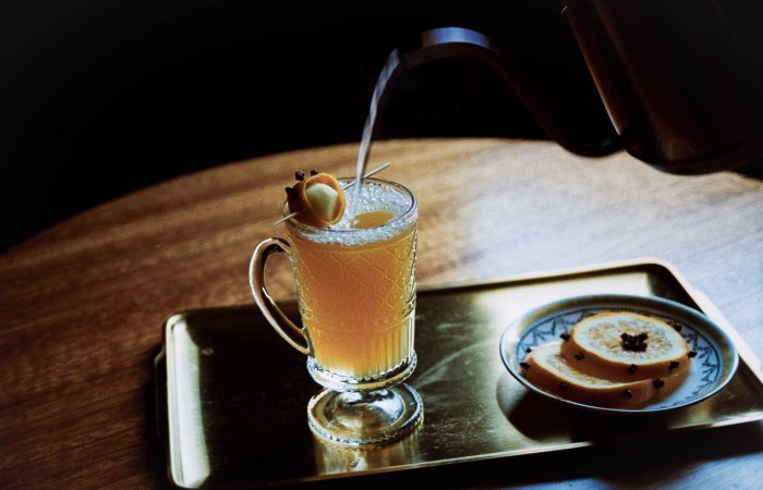 A warm citrus beverage on a tray with sliced spiced fruit, perfect for cozy moments.