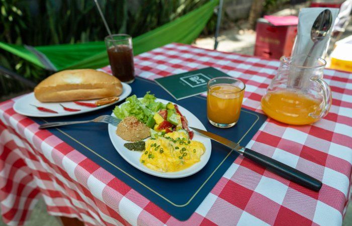 Delicious outdoor breakfast setting with scrambled eggs, salad, bread, and fresh orange juice.