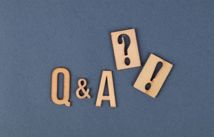 Flat lay of wooden Q&A letters with punctuation marks on a gray background.