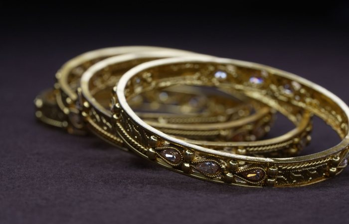 Detailed view of elegant golden bangles with intricate designs, perfect for jewelry enthusiasts.