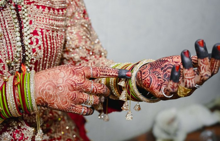 Close-up of a bride's hands adorned with intricate mehndi and colorful bangles, showcasing Indian bridal jewelry and fashion.