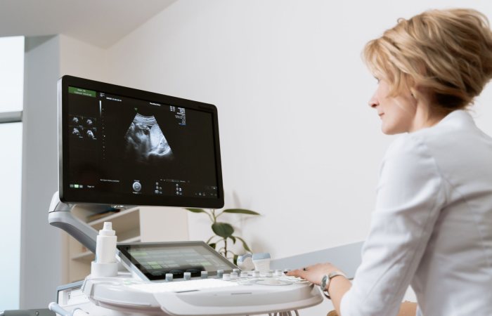 Female doctor using ultrasound scanner in modern medical clinic.