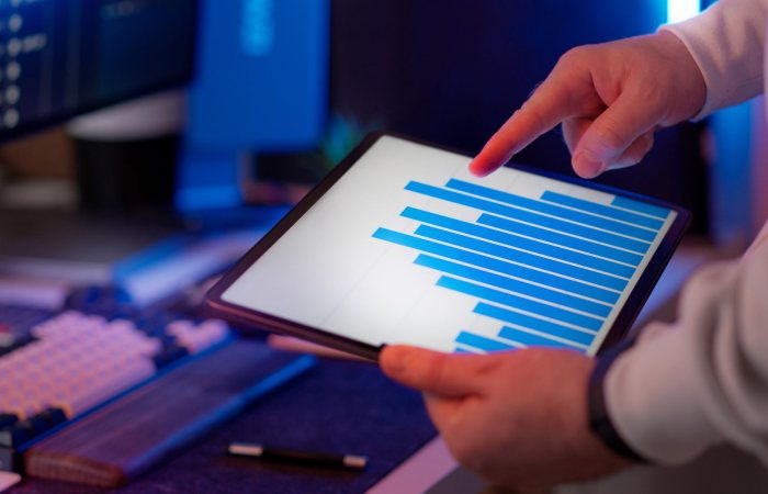 Business professional analyzing bar chart on tablet in office setting, highlighting data insights.