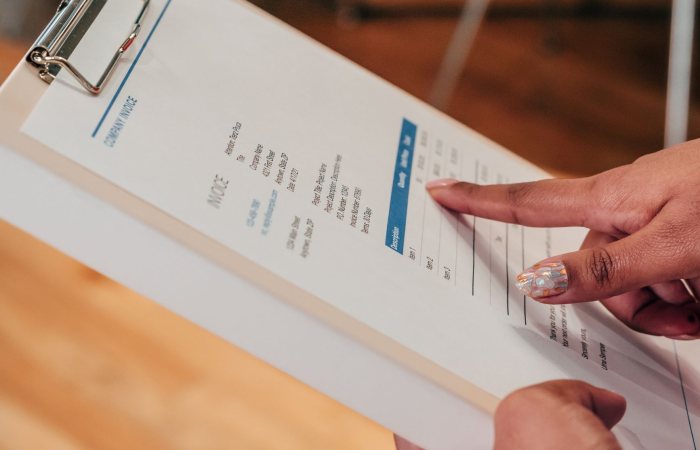 Close-up image of a person pointing to a document on a clipboard, indoors.